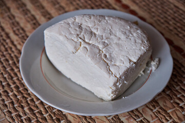 A piece of homemade cheese lies in a plate close-up. Fresh cheese. Healthy eating