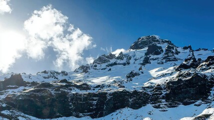 Majestic Snow-Capped Mountain Peak Under a Bright Blue Sky with Fluffy Clouds