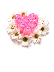 A heart made of six pink roses. The roses are surrounded by white daisies and placed and pure white background. Concept of love and affection. Abstract conceptual art.