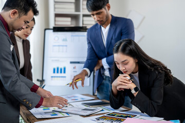 A group of people are gathered around a table with papers and graphs