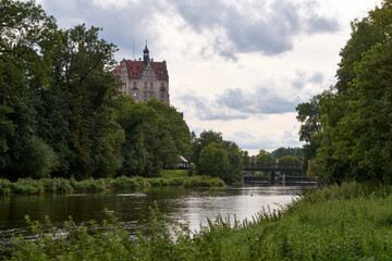 Fototapeta premium Picturesque Schloss Hohenzollern Castle Overlooking Tranquil River and Historic Bridge in Scenic German Countryside