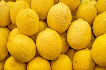 A bunch of lemons are piled on top of each other. The lemons are yellow and appear to be fresh