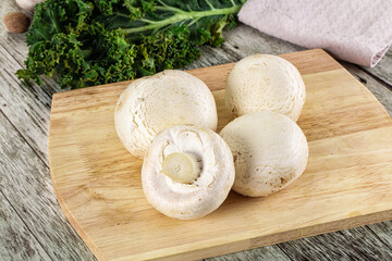 White champignon mushrooms heap over board