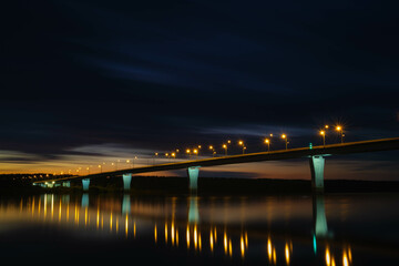 View of the road bridge at night. Glowing lights on the bridge illuminate the road. Bridge over the Vyatka River