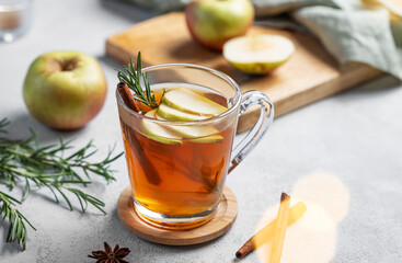 Homemade apple punch with apples, cinnamon and rosemary in a cup on a light  background