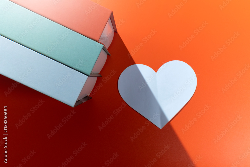 Aufkleber top view of the white heart and a row of books on a colored background