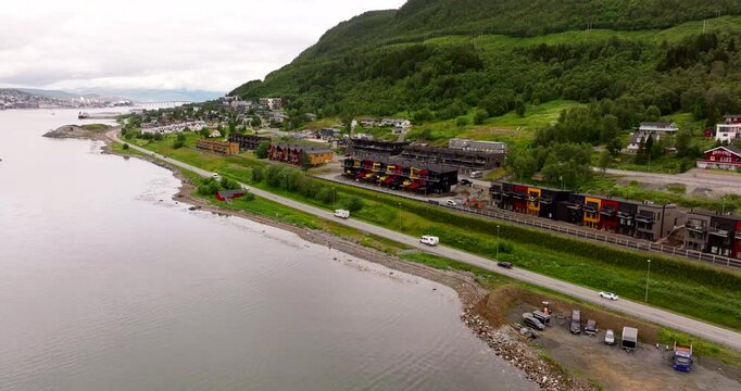 E8 road along fjord, Tromso in summer season, verdant Norwegian landscape, cloudy day, vivid colors, Northern Norway in Scandinavia. Aerial backward