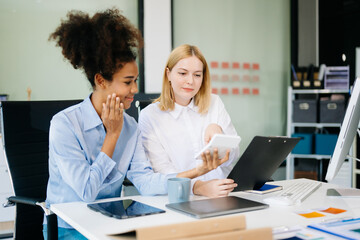 Fototapeta premium Female discussing new project with Female colleague. Young woman talking with young african woman