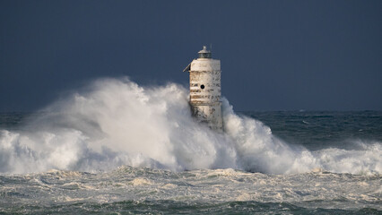 Ocean waves crashing against a lighthouse during a powerful storm at sea