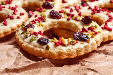 Christmas cookies decorated with white glaze, cranberries, and pistachios close-up.