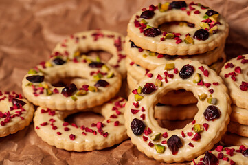 Festive cookies topped with dried fruits, nuts, and icing on a textured paper background.