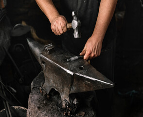 Hammering metal piece on blacksmith's anvil