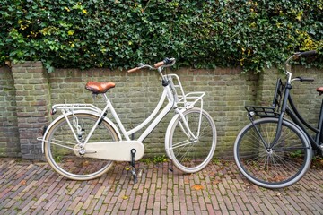 Fototapeta premium White and black bicycle leaned on brick wall beside the city street in Amersfoort