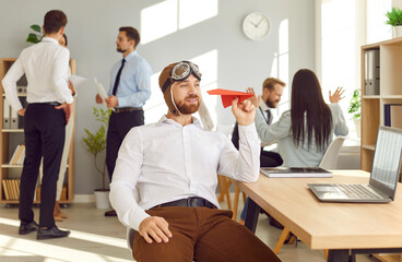 Young businessman sitting at his workplace holding a paper airplane, close-up. Employee in the...