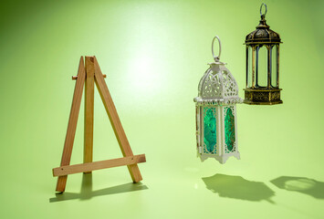 Wooden easel and Arabic lanterns hanging on a colored background. Decoration for Muslim holidays...