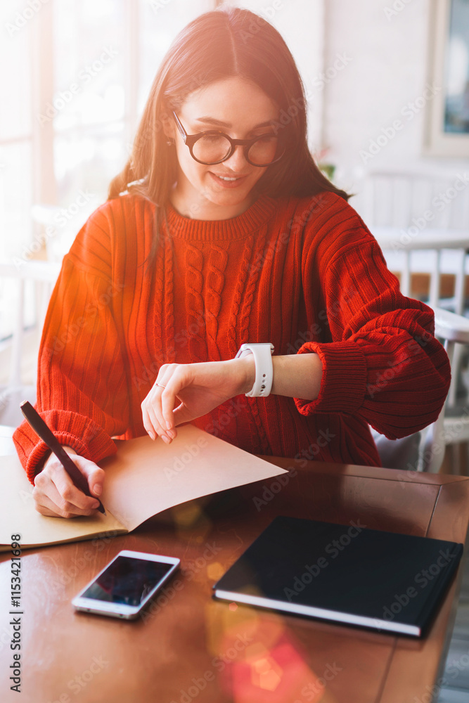 Poster positive smiling hipster girl reading incoming message on wearable smartwatch in break of studying a