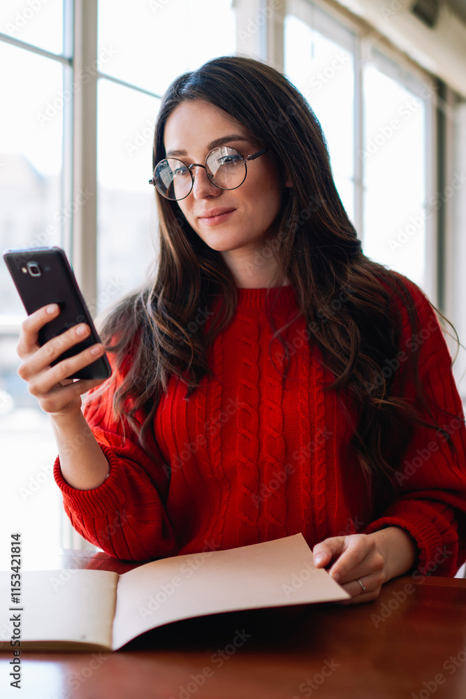 Poster caucasian female student checking notification and typing message using mobile phone sitting at cafe