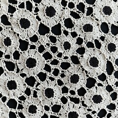Intricate lace fabric featuring floral patterns with black and cream contrasts, showcasing delicate craftsmanship and texture.