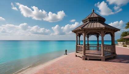 Fototapeta premium A gazebo on a paved plaza with turquoise blue water and a cloudy sky in the background