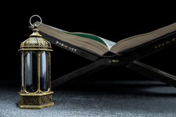 Arabic lantern and Quran on quran matt with a black background. Decoration for Muslim holidays...