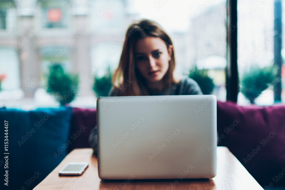 Aufkleber skilled female blogger using modern netbook for watching videos online via app while connected to wi