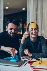 Joyful male and female sitting in campus and playing good positive game while waiting friends at cafeteria, successful caucasian studends having fun after doing homework indoors laughing at joke