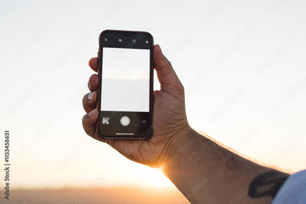 Poster cropped image of male using smartphone with blank copy space screen on background of beautiful sunse