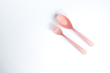 A pair of pink spoon and fork placed on a clean white surface