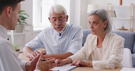 Happy elderly couple in the office talking to an insurance agent, close-up. Senior people read the contract. Broker consultation. Concept health insurance, success cooperation, happy senior