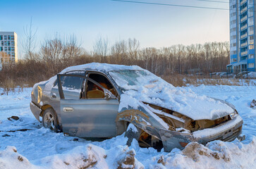A wrecked car abandoned under the snow