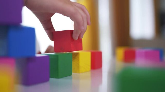 Girl daughter plays with blocks, builds. Play toddler kid concept. The child plays with blocks lifestyle and cubes, fine motor. skills. A girl plays with cubes and blocks in a building in kindergarten