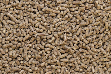 Wood pellet cat litter as background, closeup. Pressed wood, large granules. Pellets. A pile of wood granules. Texture. Wood filler for cat toilet, top view. Hygienic filler for pets