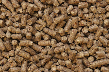Wood pellet cat litter as background, closeup. Pressed wood, large granules. Pellets. A pile of wood granules. Texture. Wood filler for cat toilet, top view. Hygienic filler for pets