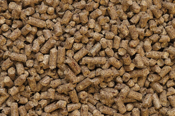 Wood pellet cat litter as background, closeup. Pressed wood, large granules. Pellets. A pile of wood granules. Texture. Wood filler for cat toilet, top view. Hygienic filler for pets