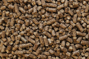 Wood pellet cat litter as background, closeup. Pressed wood, large granules. Pellets. A pile of wood granules. Texture. Wood filler for cat toilet, top view. Hygienic filler for pets