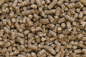 Wood pellet cat litter as background, closeup. Pressed wood, large granules. Pellets. A pile of wood granules. Texture. Wood filler for cat toilet, top view. Hygienic filler for pets