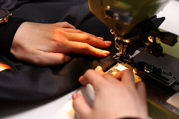 Woman working with sewing machine in professional workshop, closeup