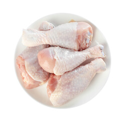 Raw chicken drumsticks on plate against white background, top view