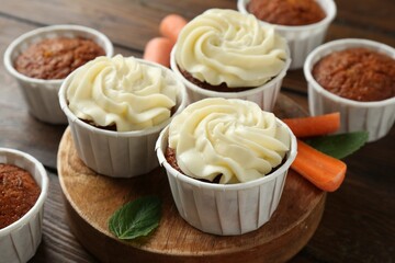 Tasty carrot muffins and fresh vegetable on wooden table, closeup