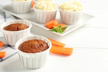 Tasty carrot muffins and fresh vegetables on white wooden table, closeup. Space for text