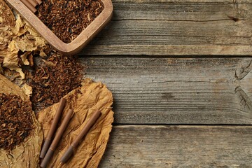 Tobacco, dried leaves and cigarettes on wooden table, flat lay. Space for text
