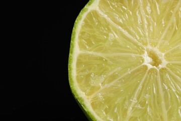 Half of fresh lime on black background, closeup. Space for text