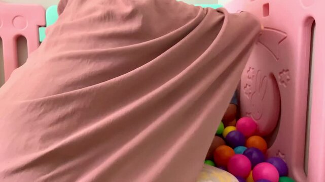 A child who lives with Cerebral palsy and wears a nasogastric tube or NGT on his nose is playing in a pool full of colorful balls