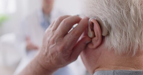 Senior elderly gray-haired man sitting with male doctor in medical clinic wearing modern hearing aid in ear listening recommendations. Hearing loss and ear problems concept. 4k video.