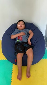 Children who use NGT (nasogastric tube) or a probe on their nose are sleepy while sitting on a blue bean-shaped sofa