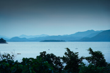 Blue scene of the Kaeng Krachan reservoir with fishing boat and tourist rowing canoe