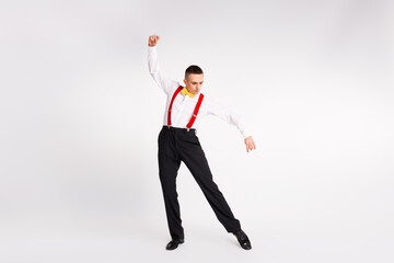 Young man performs vintage dance move in elegant attire with white background