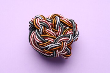Colorful ropes tied in knot on violet background, top view. Unity concept