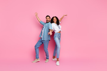 Happy young couple celebrating together against a pink background