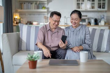 An elderly couple sits together in their cozy living room, smiling and enjoying a moment as they look at something on a smartphone. Their warmth and affection capture a peaceful home atmosphere.